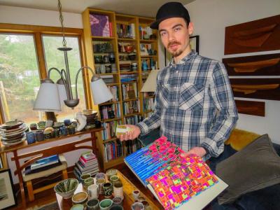 Gleason holds a sketchbook with his street art inspired drawings in his left hand and a pottery piece influenced by the drawings in his right.