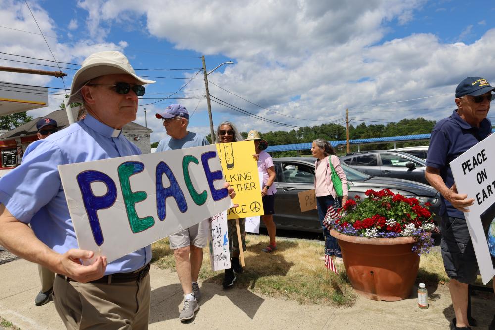 Reverend Daniel Bernier of the Church of the Good Shepherd holds up a sign for peace