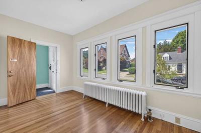Unit 1 front room with a row of windows, a radiator and hardwood floors at 370 Maple Street, New Bedford