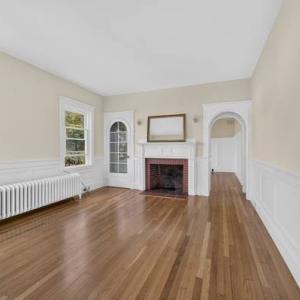 Unit 1 living room with a brick fireplace, wainscoting and an arched doorway at 370 Maple Street, New Bedford